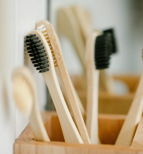 Wooden natural toothbrushes placed in timber container on blurred background at home in daytime