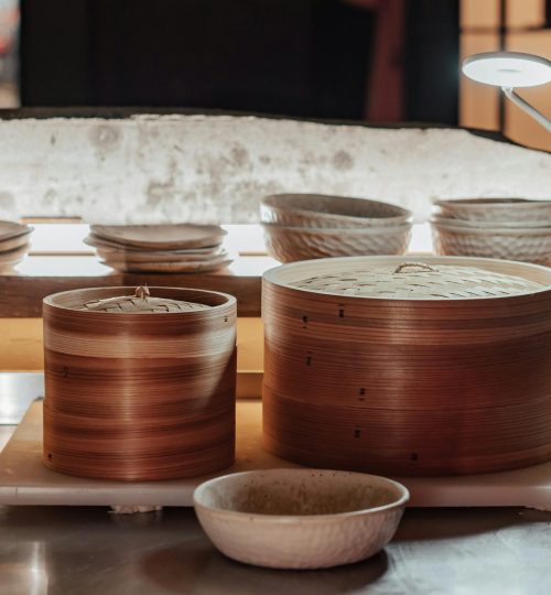 Close-up of bamboo steamers and kitchenware on a metallic countertop.
